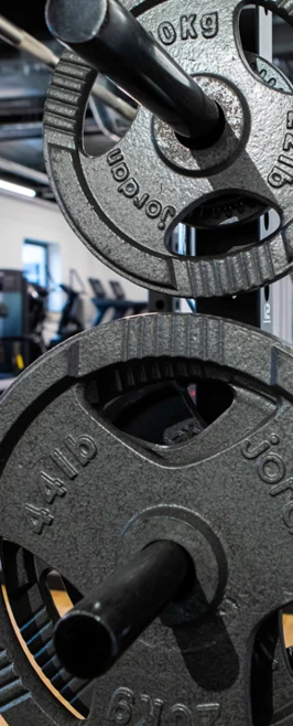 Close-up view of weight plates on a squat rack in a well-equipped college gym. Close-up view of weight plates on a squat rack in a well-equipped college gym.